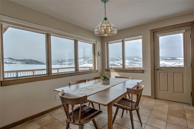 dining area featuring light tile patterned floors, a notable chandelier, and baseboards