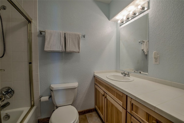 bathroom with toilet, vanity, shower / washtub combination, and a textured wall