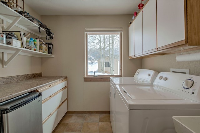 clothes washing area featuring independent washer and dryer, cabinet space, and baseboards