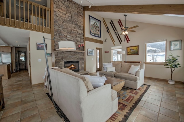 living room featuring light tile patterned floors, baseboards, a ceiling fan, a stone fireplace, and beam ceiling