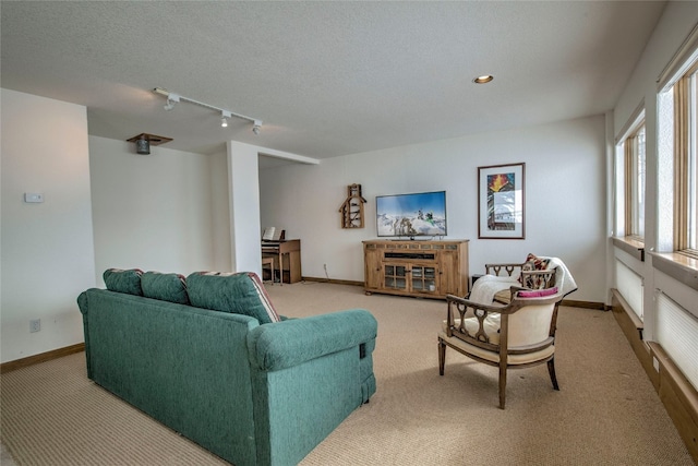 living room with track lighting, carpet, a textured ceiling, and baseboards