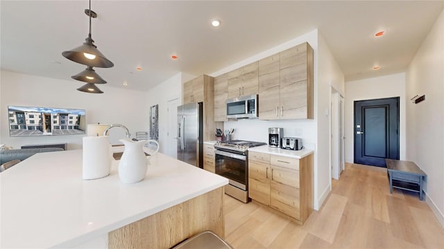 kitchen with decorative light fixtures, light countertops, appliances with stainless steel finishes, light brown cabinets, and modern cabinets