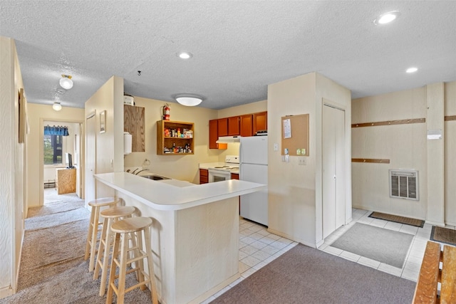 kitchen with white appliances, a peninsula, light countertops, a kitchen bar, and a sink