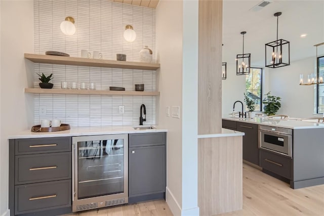 bar with hanging light fixtures, decorative backsplash, sink, oven, and wine cooler