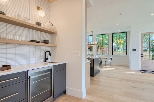 bar with wine cooler, light hardwood / wood-style floors, sink, backsplash, and gray cabinets