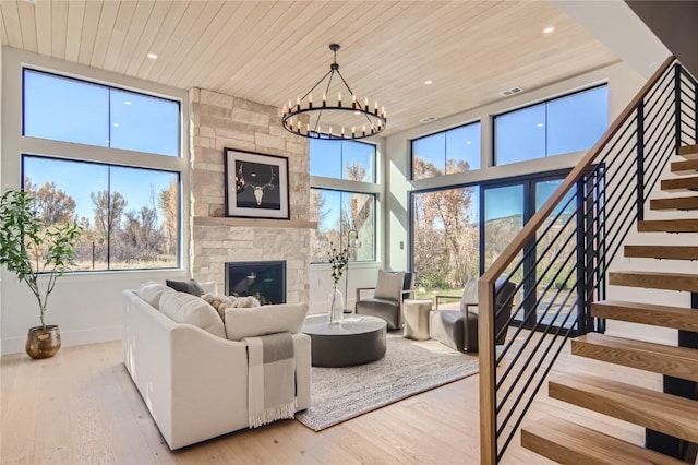 living room with a fireplace, an inviting chandelier, light hardwood / wood-style floors, and wood ceiling