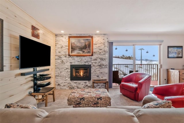 carpeted living room featuring wooden walls and a large fireplace