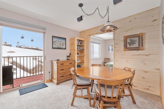 carpeted dining area featuring wood walls