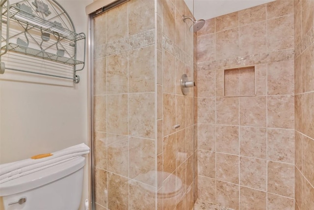 bathroom featuring toilet and a shower with door