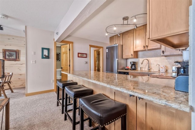 kitchen featuring light brown cabinetry, sink, high end refrigerator, light colored carpet, and light stone countertops