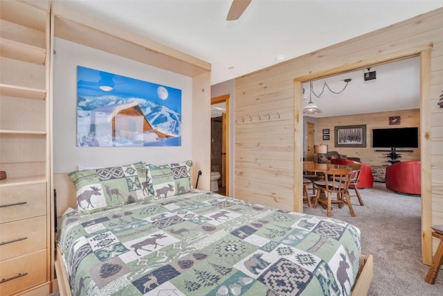 carpeted bedroom featuring ceiling fan and wooden walls