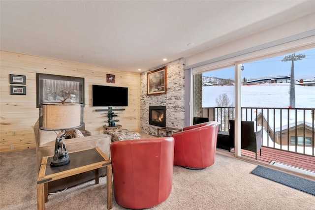 carpeted living room featuring a fireplace and wood walls