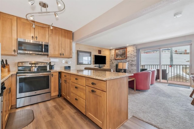 kitchen featuring beamed ceiling, light stone counters, kitchen peninsula, stainless steel appliances, and light carpet