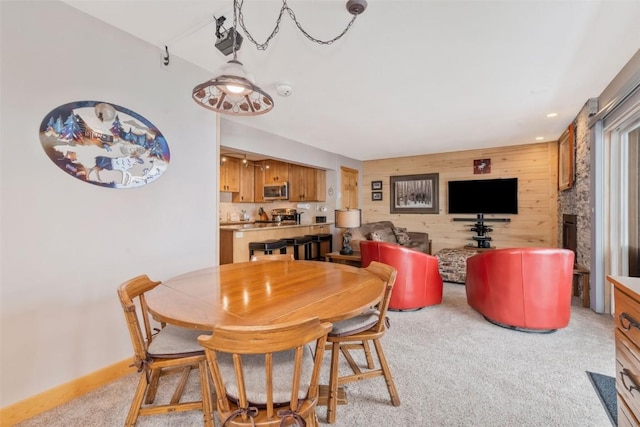 carpeted dining room featuring wood walls