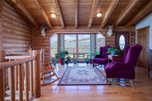 sitting room featuring rustic walls, beamed ceiling, a mountain view, wood ceiling, and light wood-type flooring