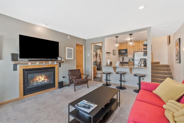 living room featuring carpet floors, stairway, a glass covered fireplace, and baseboards