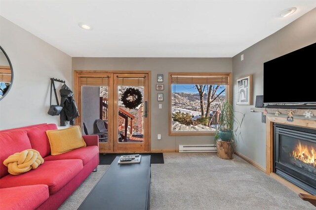 living area featuring carpet, baseboards, baseboard heating, and a glass covered fireplace