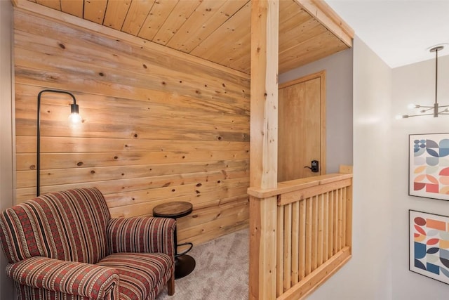 sitting room with wooden ceiling, carpet, and wood walls