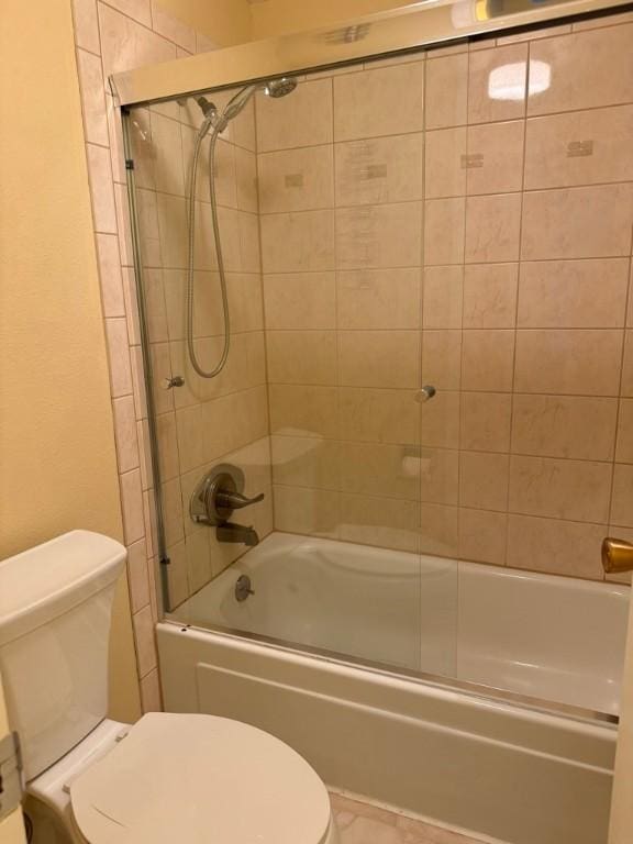 bathroom featuring toilet and combined bath / shower with glass door