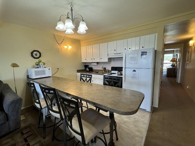 kitchen featuring kitchen peninsula, white appliances, sink, a notable chandelier, and white cabinets