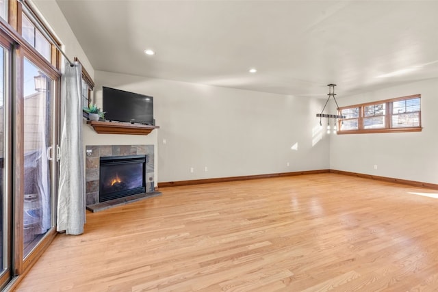 unfurnished living room with a fireplace, light wood-style flooring, and baseboards