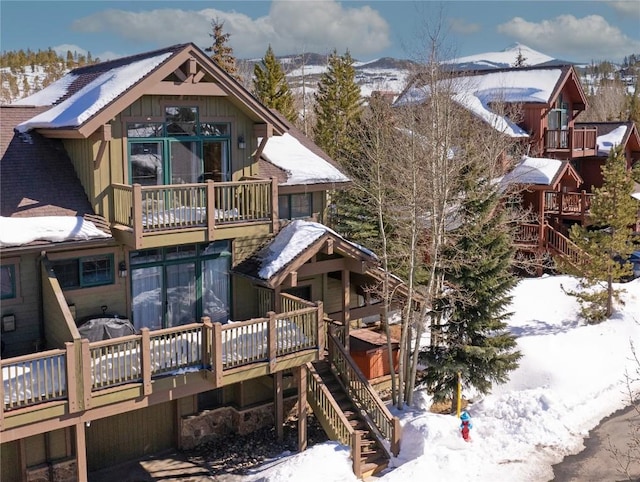 snow covered house featuring stairway