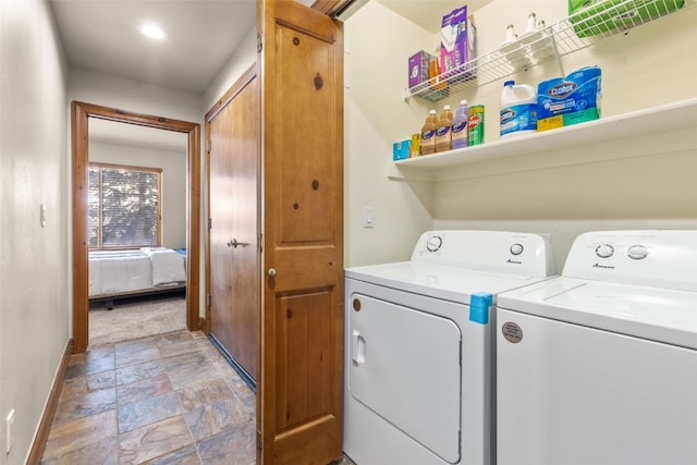 laundry room featuring laundry area, stone finish floor, washing machine and dryer, and baseboards