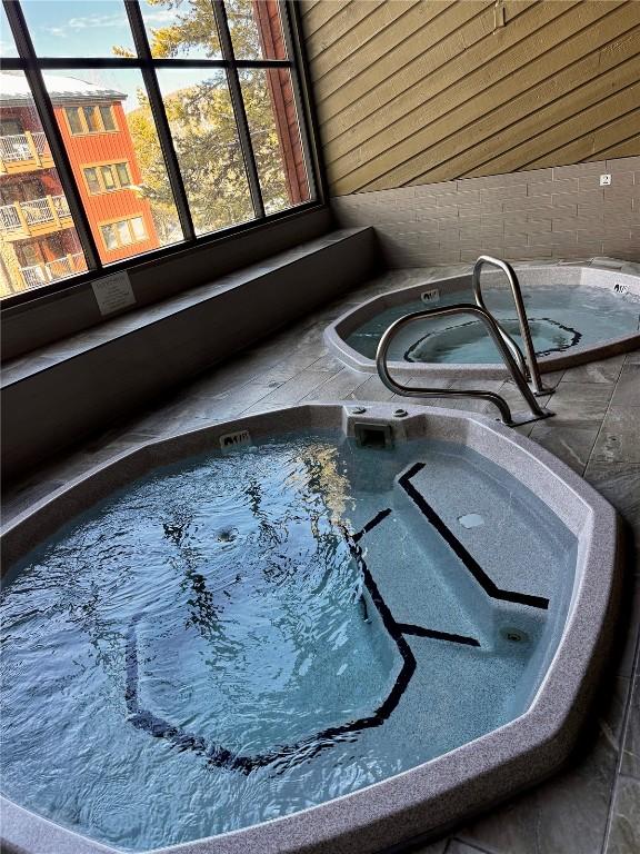 interior details featuring a jacuzzi and wooden walls