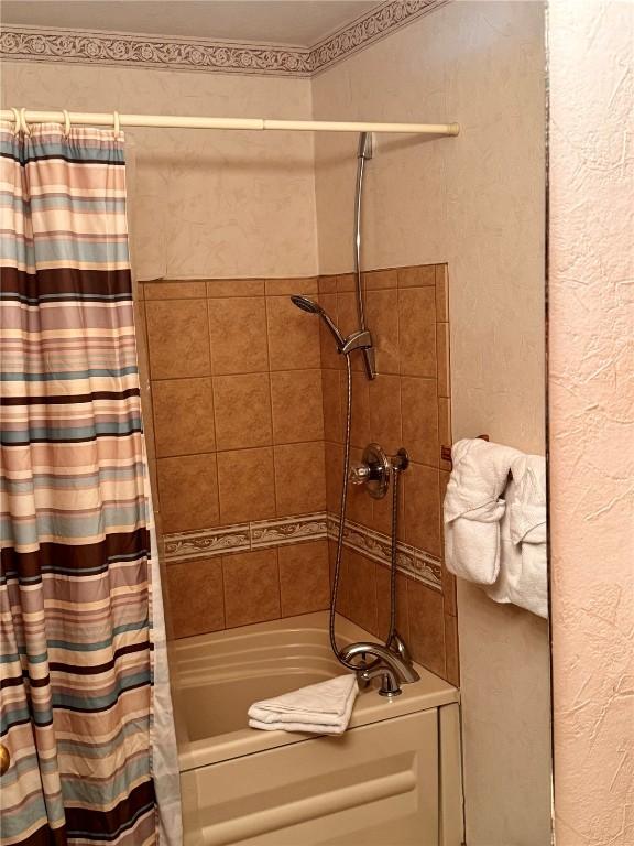 bathroom with shower / bath combo and a textured wall