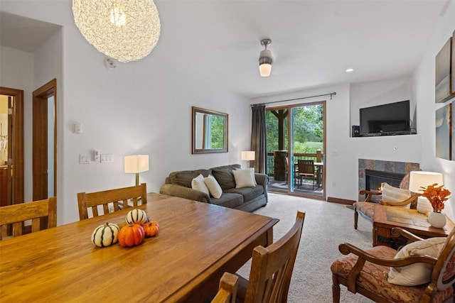 carpeted dining space featuring a tile fireplace and a chandelier