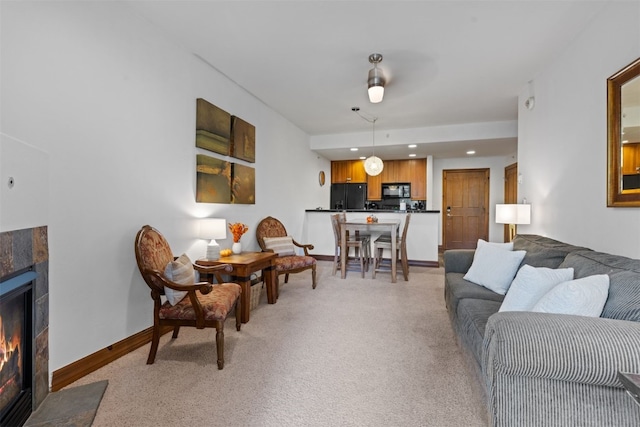 living room with ceiling fan, light carpet, and a tile fireplace