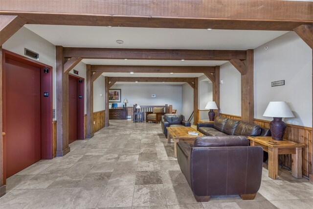 living room featuring beam ceiling, elevator, and wooden walls