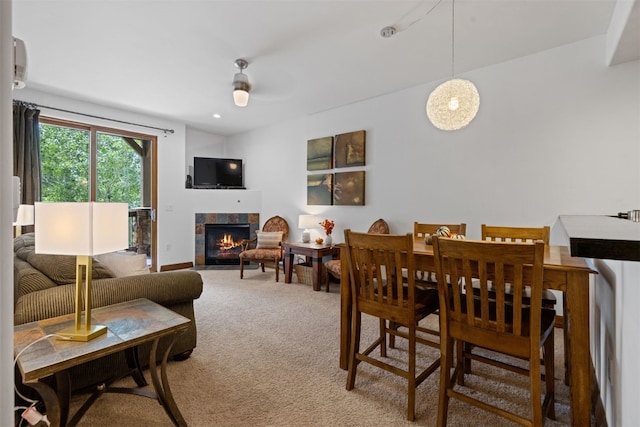 carpeted dining area with ceiling fan and a tiled fireplace