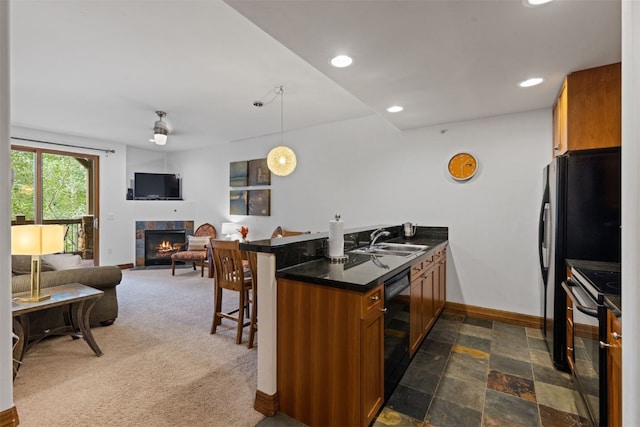 kitchen featuring stove, a tile fireplace, a kitchen breakfast bar, sink, and kitchen peninsula