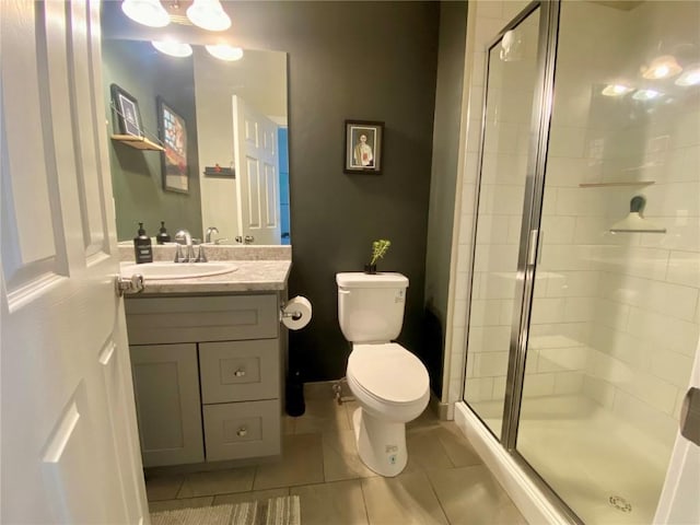 bathroom with tile patterned flooring, a stall shower, toilet, and vanity