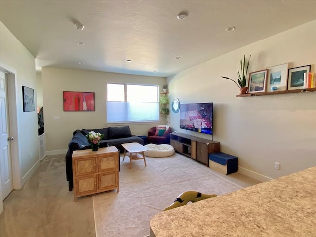 living area featuring baseboards and light carpet