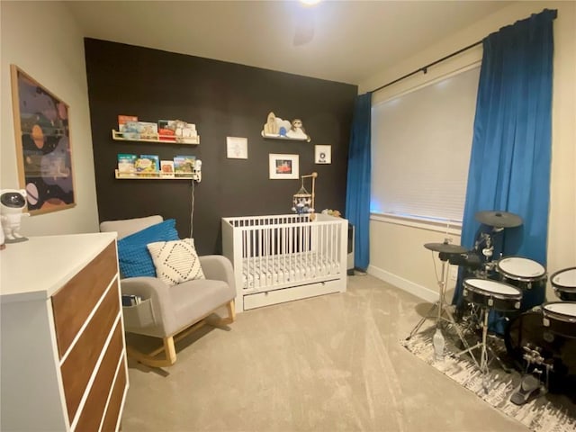 carpeted bedroom featuring a crib and baseboards