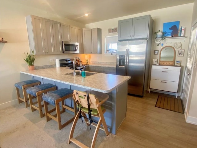 kitchen with visible vents, a breakfast bar, a peninsula, stainless steel appliances, and a sink