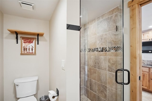 bathroom featuring vanity, toilet, and a shower with shower door