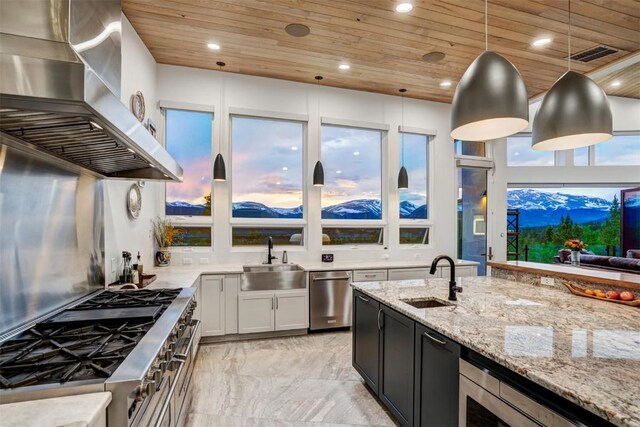 kitchen featuring pendant lighting, wooden ceiling, sink, and wall chimney range hood