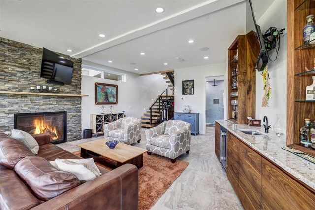 living room featuring a stone fireplace and sink