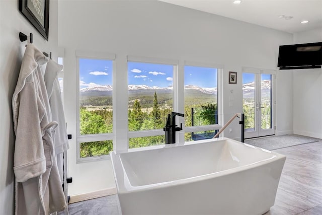 bathroom featuring french doors, a tub to relax in, and sink