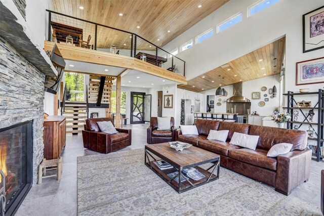 living room featuring a high ceiling, a stone fireplace, and wooden ceiling