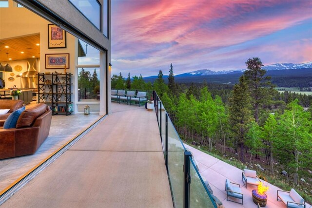 patio terrace at dusk featuring a mountain view, a balcony, and an outdoor living space