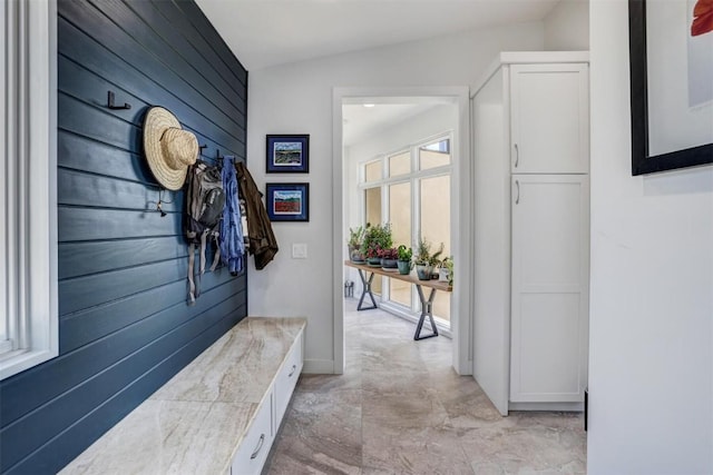 mudroom with wood walls and lofted ceiling