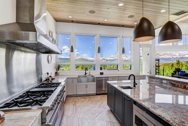 kitchen featuring a mountain view, wall chimney exhaust hood, wooden ceiling, and decorative light fixtures