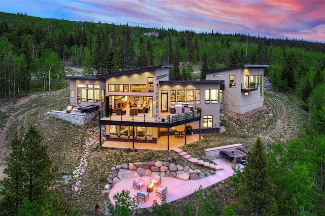 back house at dusk featuring a patio