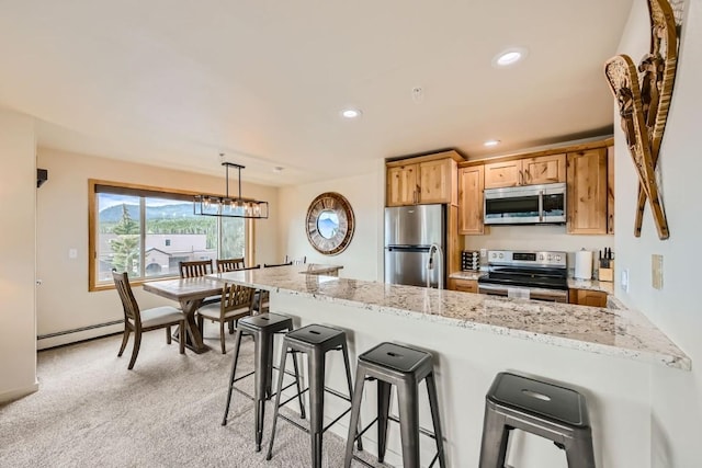 kitchen featuring stainless steel appliances, a baseboard radiator, recessed lighting, a peninsula, and a kitchen bar