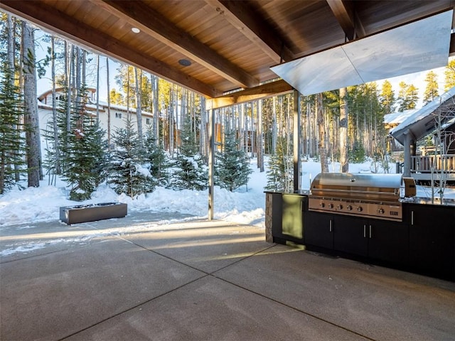 snow covered patio featuring an outdoor kitchen and a grill