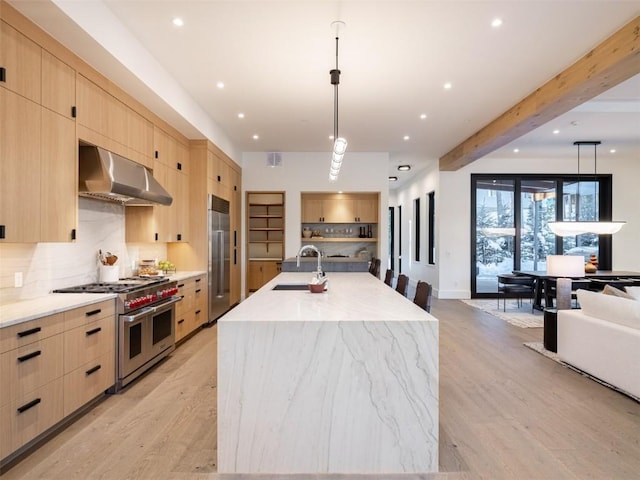 kitchen with beam ceiling, a kitchen island with sink, light brown cabinetry, and premium appliances